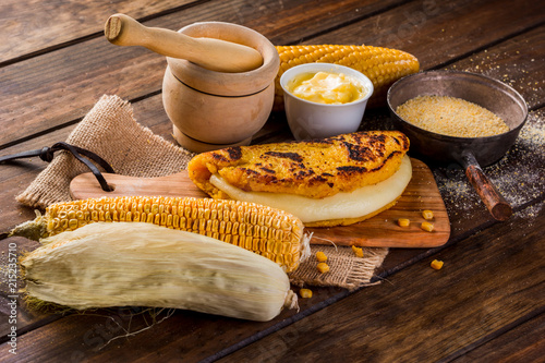 Typical Venezuelan cuisine, Top view of a wooden table with several ingredients for the preparation of Cachapas with cheese, corn, butter, ground corn and white cheese photo