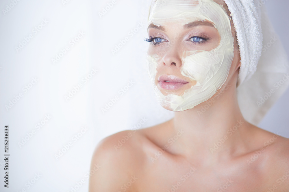 happy woman with a towel on her head puts on face mask