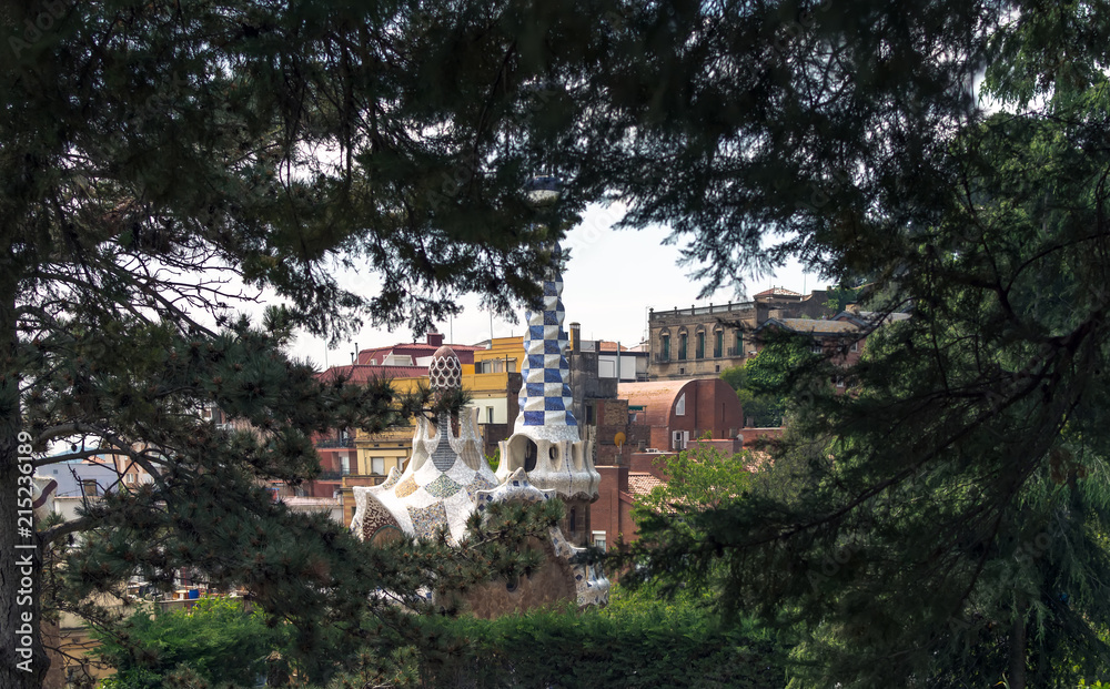View to the fairytale gingerbread lodge with rooftop terrace through pine tree branches in Park Guell, Barcelona, Spain.