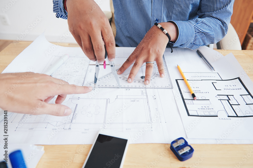 Crop hand of chief pointing at blueprint of unrecognizable Indian employee in office Crop hand of chief pointing at blueprint of unrecognizable Indian employee in office