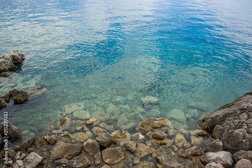 calm rest concept of blue water surface and small waves with stones and empty space for copy or text