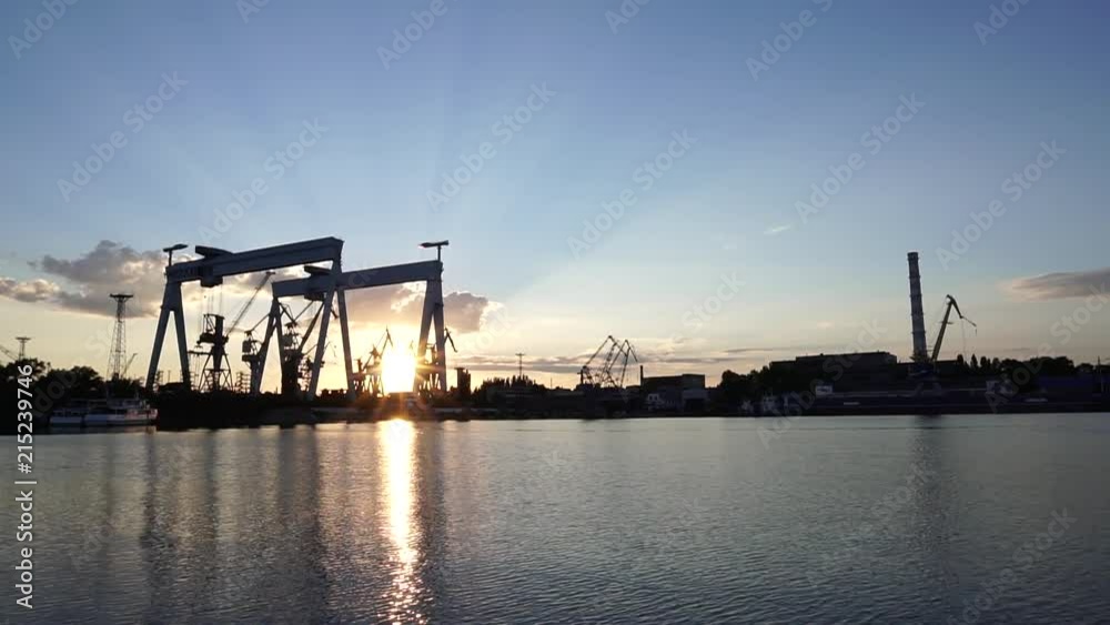 Magnificent steady panorama view on innovative crane production shipbuilding factory silhouette in warm evening sunset Magnificent steady panorama view on innovative crane production shipbuilding factory silhouette in warm evening sunset