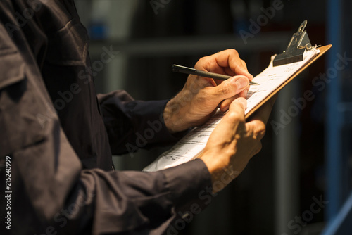 Factory worker writing on clipboard photo