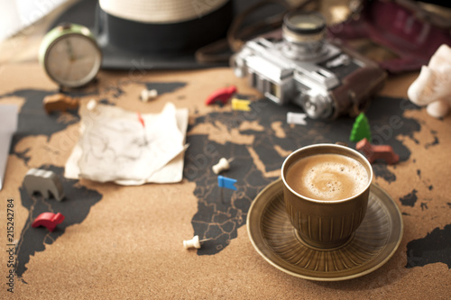 A cup of fragrant coffee on the map, an old camera and a route plan, a vintage photo. Travel and holidays. Copy space.