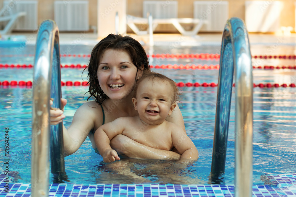 Mother playing with son in swimming pool. Both mom and toddler are in  water, they are happy. The little boy is laughing showing baby teeth.  Active family lifestyle concept Stock Photo |