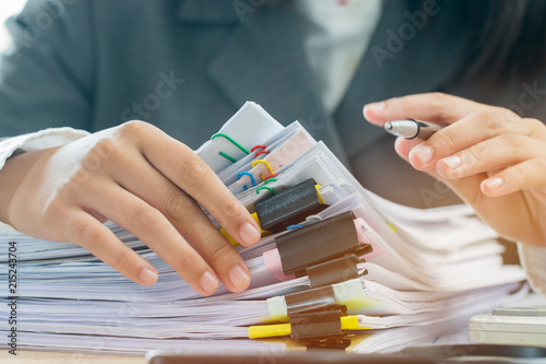 Accounting planning budget concept : Business woman offices working for arranging documents unfinished stack of document papers with pen, calculator, clip papers on busy office desk photo