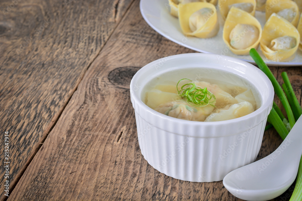 Homemade meat and prawn wonton soup in white bowl on wooden table background.
Homemade meat and prawn wonton soup in white bowl on wooden table background.