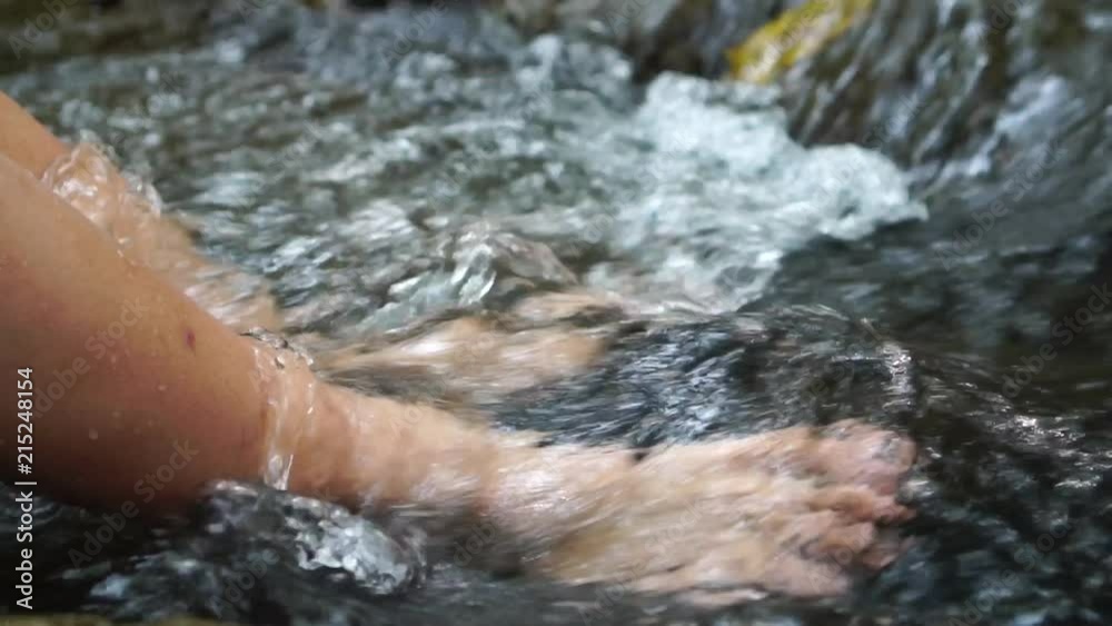 Relaxing for life, natural therapy concept : Young man's feet standing on rocks with clear, cold water. Feel comfortable and relax in nature of forest with water flowing on summer day, slow motion Relaxing for life, natural therapy concept : Young man's feet standing on rocks with clear, cold water. Feel comfortable and relax in nature of forest with water flowing on summer day, slow motion
