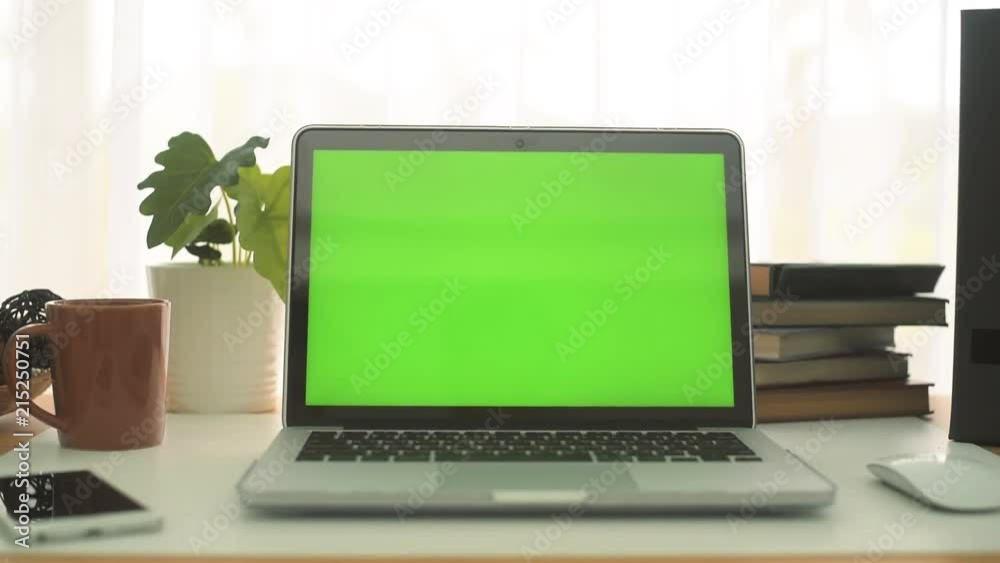A laptop computer with a key green screen set on work office table. A laptop computer with a key green screen set on work office table.