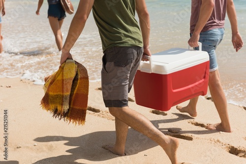 Male friends carrying esky in the beach photo