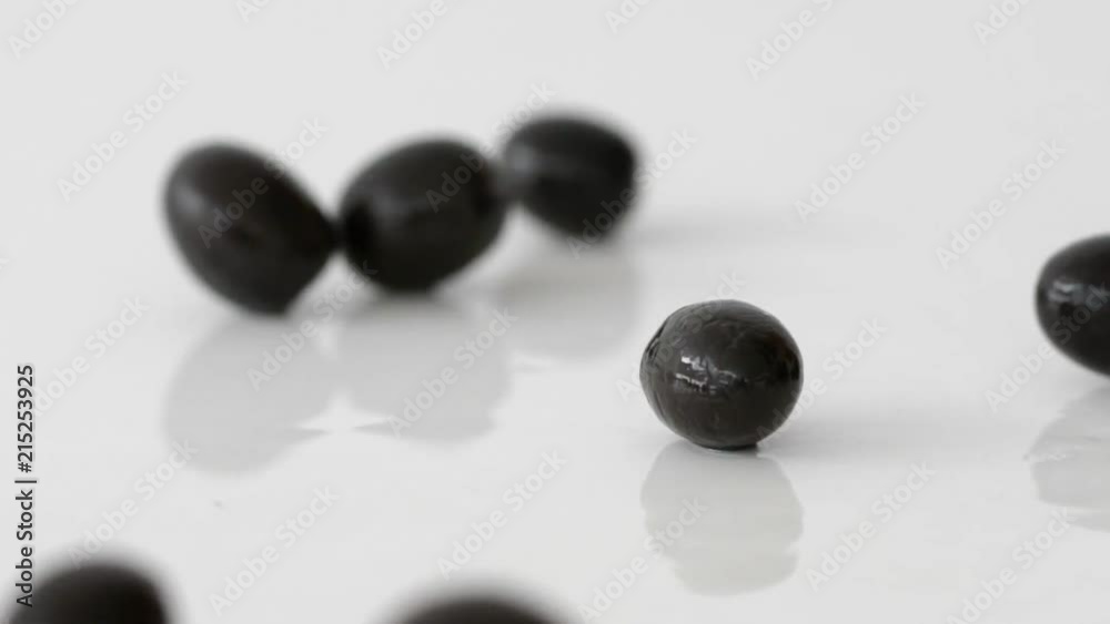 Black olives roll on the table in slow motion Black olives roll on the table in slow motion
