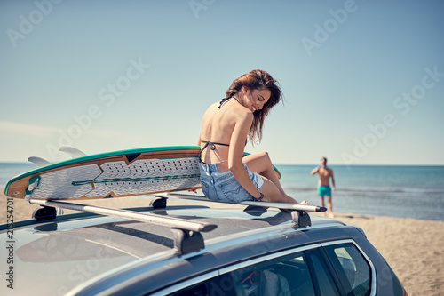 beautiful surfer girl sitting on the car and getting ready for surfing. © luckybusiness