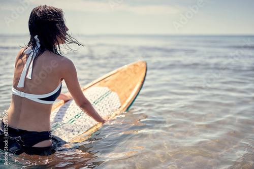 beautiful surfing woman on surf longboard surfboard board on sunrise in the ocean. © luckybusiness