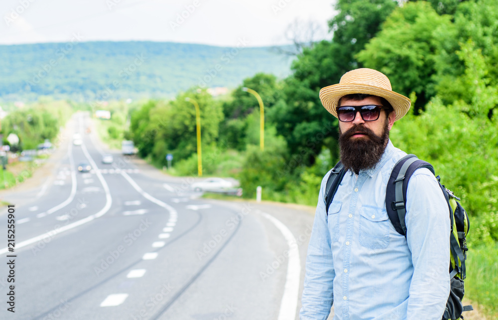 Man at edge of highway looking for transport. On the road. Hitchhiking means transportation that gained asking strangers for ride in their car. Hitchhiker try to stop transport to get to destination Man at edge of highway looking for transport. On the road. Hitchhiking means transportation that gained asking strangers for ride in their car. Hitchhiker try to stop transport to get to destination