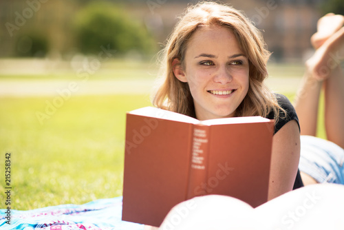 Junge Frau liegt im Park und liest ein Buch