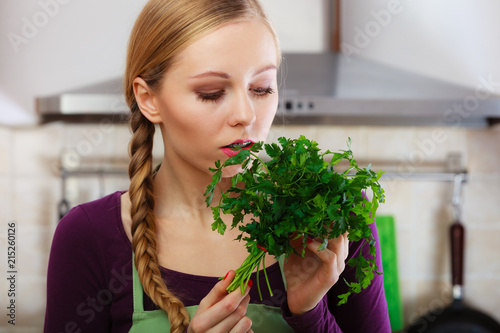 Woman in kitchen holds green aromatic parsley