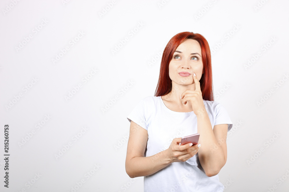 Young beautiful woman with long red hair, thinking facial expression & pose holding mobile cell phone in hands. Attractive thoughtful female with smartphone in hands. Background, copy space, close up. Young beautiful woman with long red hair, thinking facial expression & pose holding mobile cell phone in hands. Attractive thoughtful female with smartphone in hands. Background, copy space, close up.