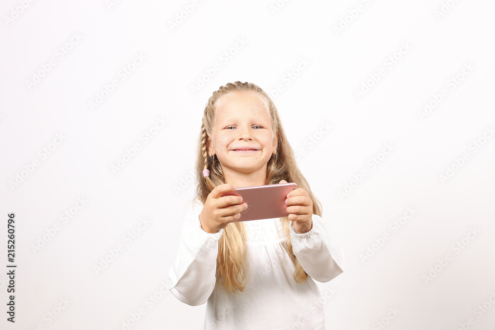 Portrait of positive & funny four year old blonde little girl, holding mobile cell phone, smiling at camera, taking selfies. Childhood & technology concept. Isolated background, copy space, close up. Portrait of positive & funny four year old blonde little girl, holding mobile cell phone, smiling at camera, taking selfies. Childhood & technology concept. Isolated background, copy space, close up.