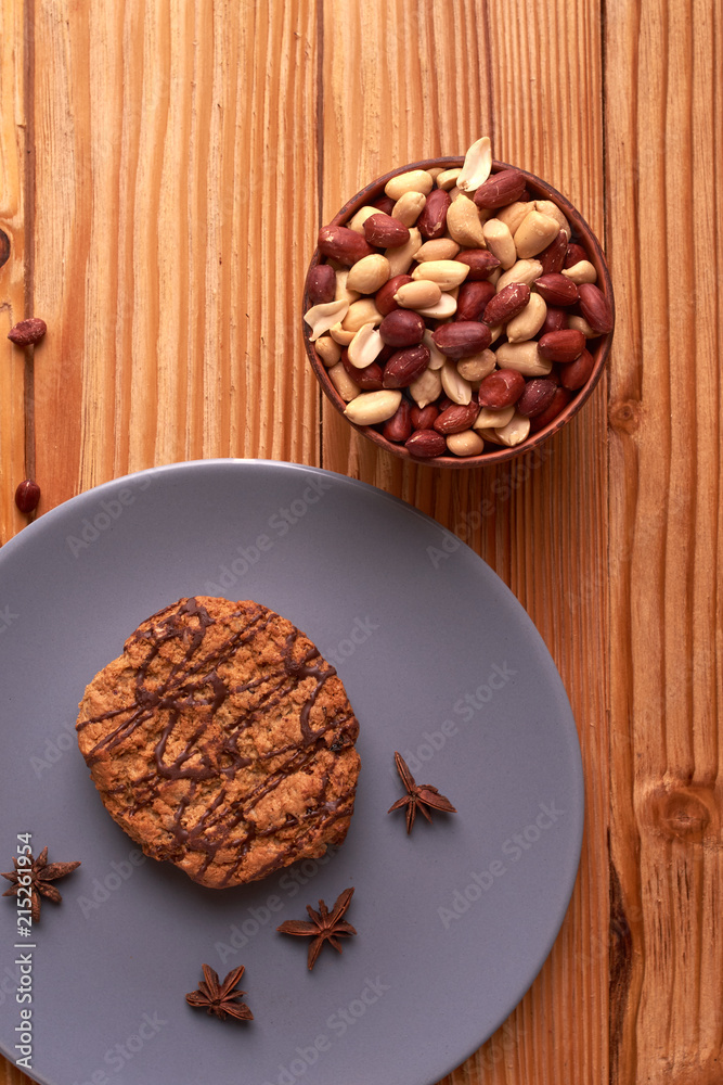 Fried Roasted peanut seed in clay bowl and chocolate cookies on plate. top view Fried Roasted peanut seed in clay bowl and chocolate cookies on plate. top view