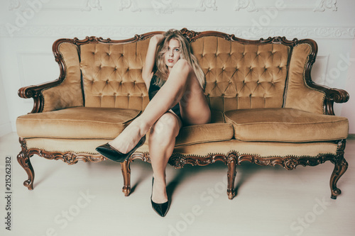 Beautiful adult lady with a gorgeous ass sitting on the royal couch. Model is dressed in fashionable lingerie. Concept of afterparty style and sexual fantasies