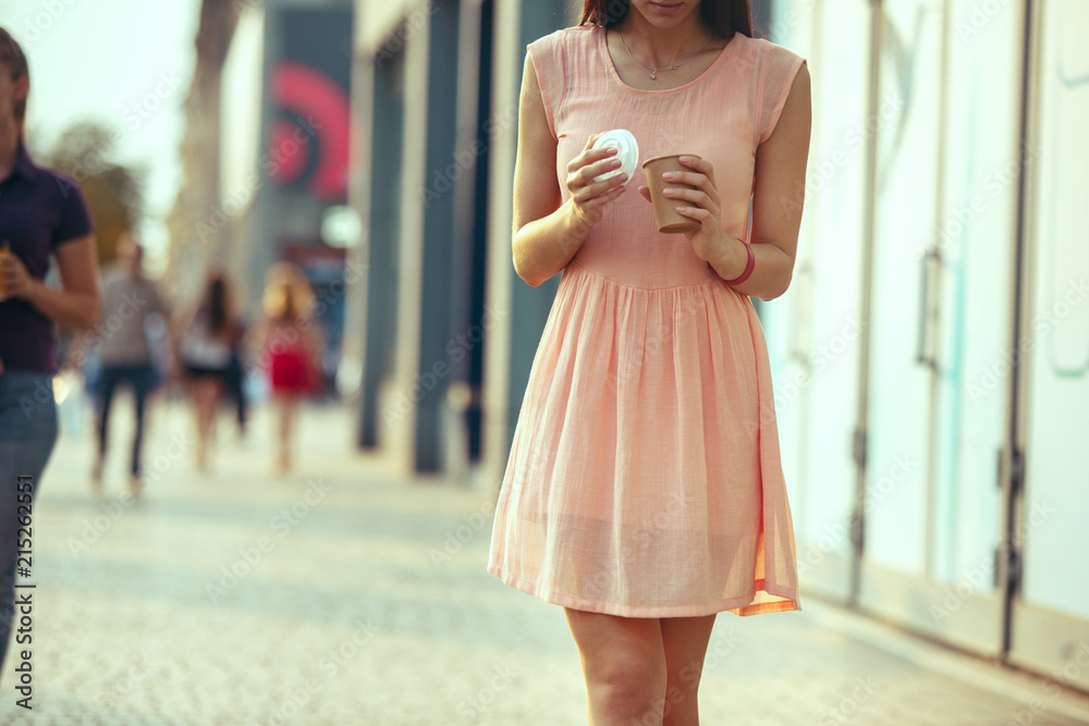 Beautiful woman holding paper coffee cup and enjoying the walk in the city