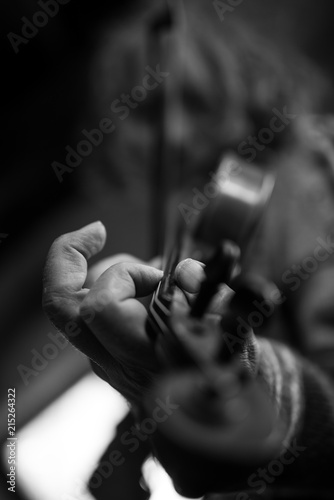 Greyscale image of elderly male musician with dirty nails playing a violin