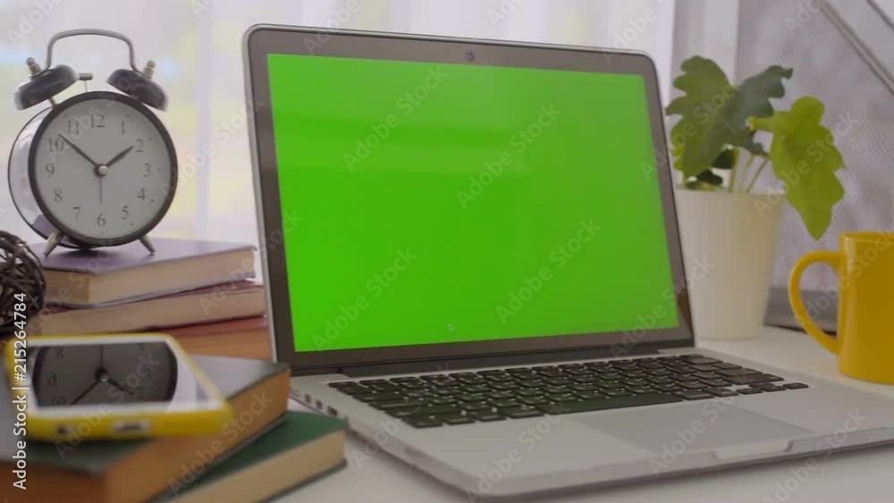 A laptop computer with a key green screen set on work office table. A laptop computer with a key green screen set on work office table.
