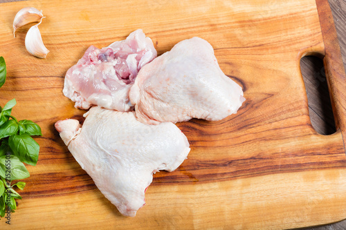 Raw chicken thighs with skin and bone on chopping board