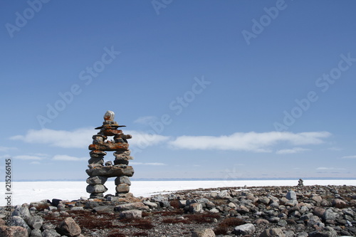 Inukshuk or Inuksuk landmark with frozen bay in the background near Arviat, Nunavut
