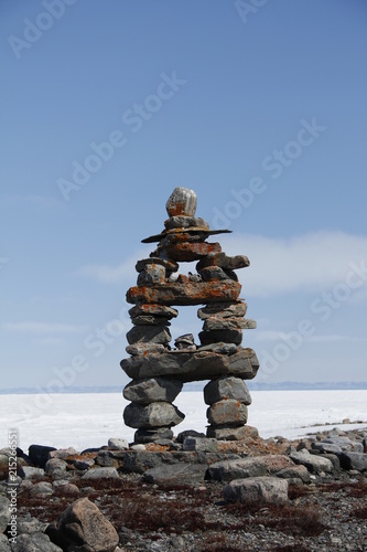 Inukshuk or Inuksuk landmark with frozen bay in the background near Arviat, Nunavut