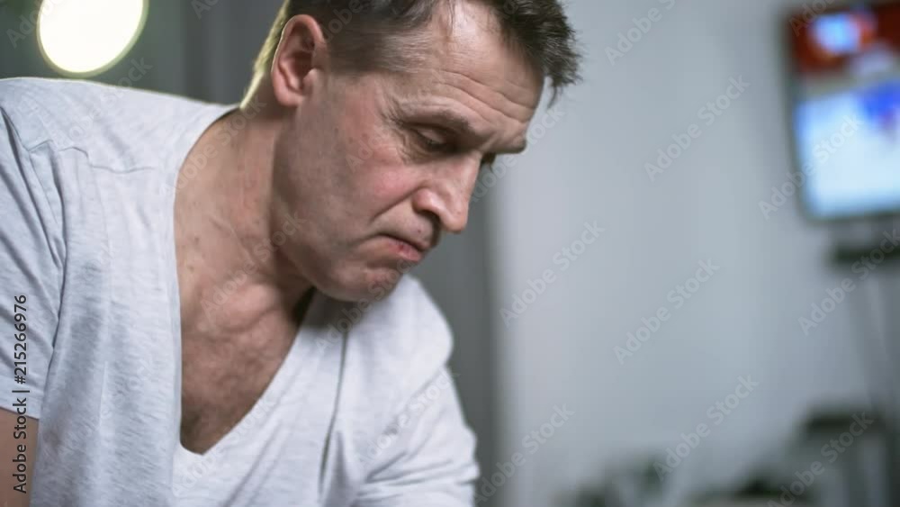 Close up shot of fit middle-aged man performing one-arm bicep curls with dumbbells in living room at home Close up shot of fit middle-aged man performing one-arm bicep curls with dumbbells in living room at home