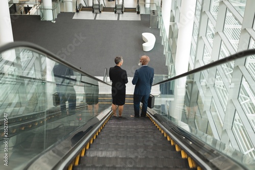 Businessman and businesswoman going down on an escalator