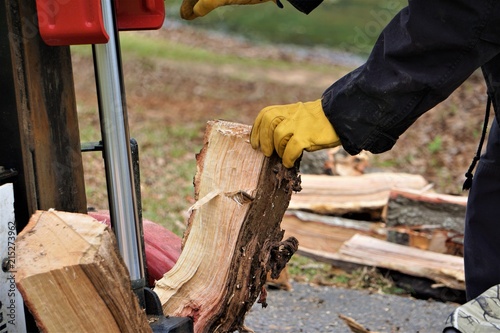 A man working with the firewood to split the logs by the machine on the driveway in the garden, Winter in GA USA.