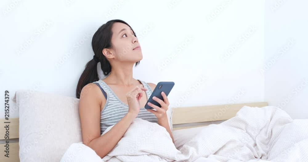 Woman using mobile phone app to control the lighting at home, smart home concept Woman using mobile phone app to control the lighting at home, smart home concept