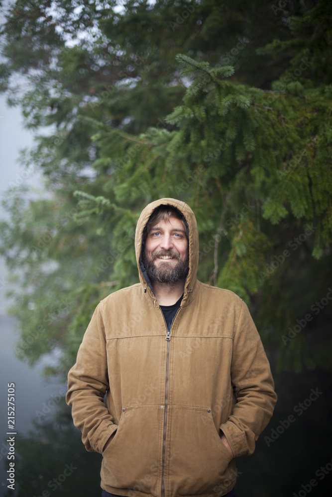Man in hooded jacket stands on a dock in Fletcher Bay on a foggy morning. Man in hooded jacket stands on a dock in Fletcher Bay on a foggy morning.