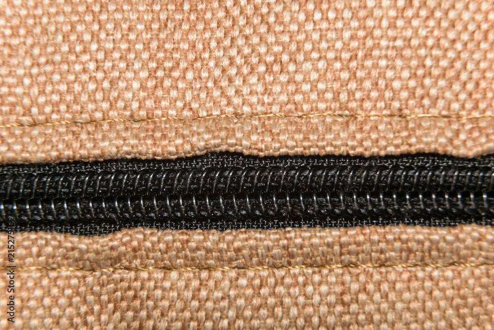 Black closed zipper on a beige fabric Black closed zipper on a beige fabric