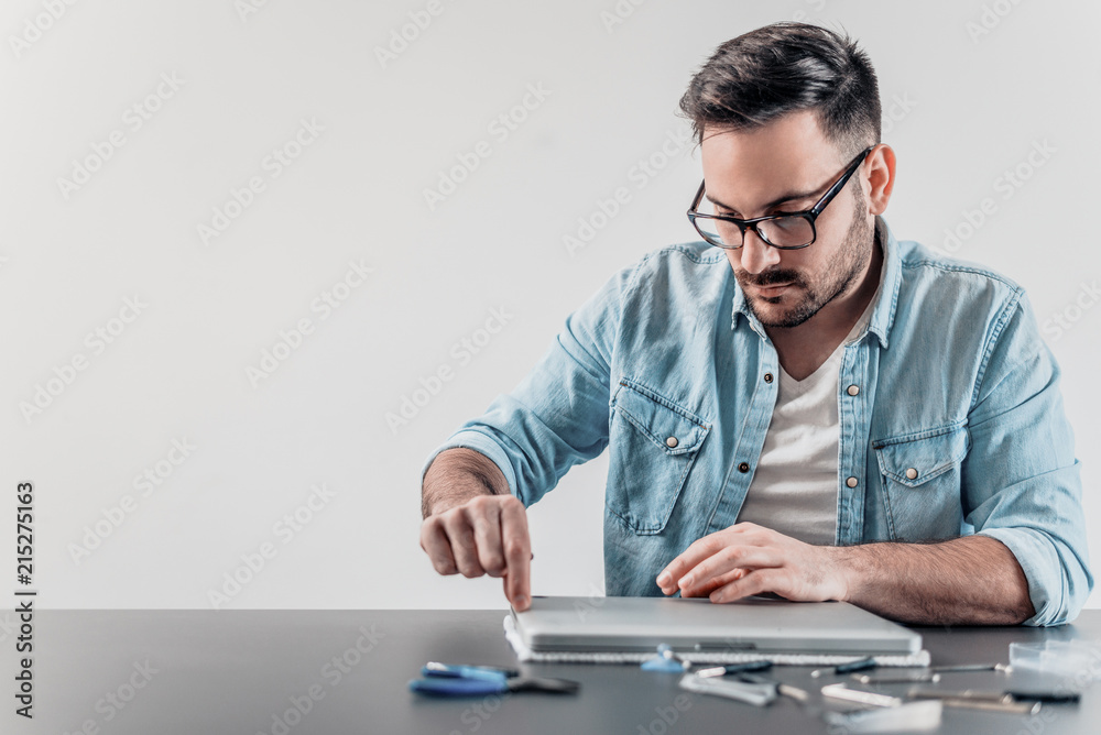 Young computer technician disassembling laptop. Young computer technician disassembling laptop.
