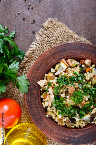 Tabbouleh - hot salad of couscous, meat, fried vegetables and parsley in a clay bowl. Lebanese cuisine. The top view