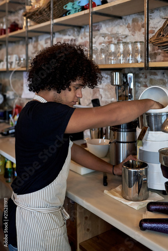 Side view of male worker in apron working in cafe bar and pouring freshly brewed coffee. photo