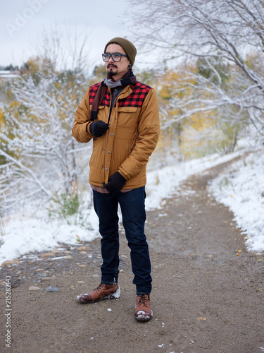 A man zips up his autumn jacket on a snowy path photo