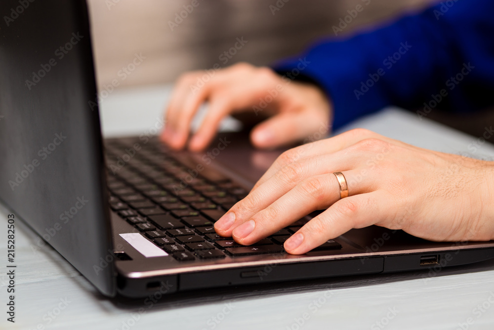 Young man working with laptop, man's hands on notebook computer, business person at workplace Young man working with laptop, man's hands on notebook computer, business person at workplace