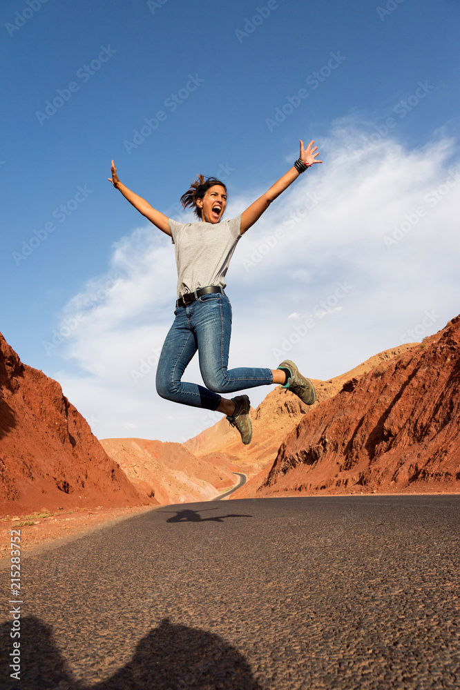 A woman jumping in the air on a desert highway in Morocco A woman jumping in the air on a desert highway in Morocco