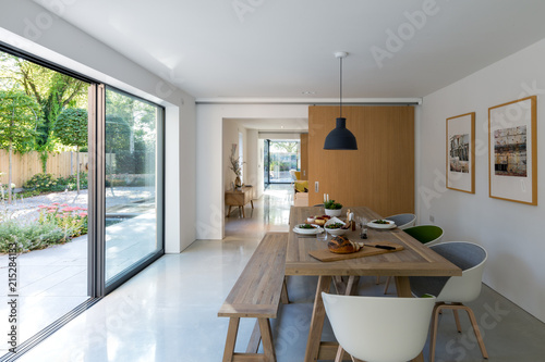 Contemporary dining room with views to the garden through large glass areas. Table set for lunch. photo