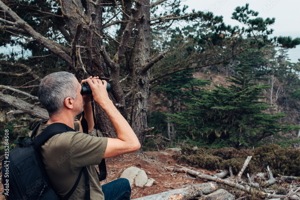 Backpacking hiker looking through binoculars Backpacking hiker looking through binoculars