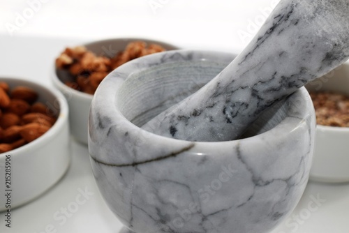 Marble Mortar and near it two white pottery containers with almonds and walnuts