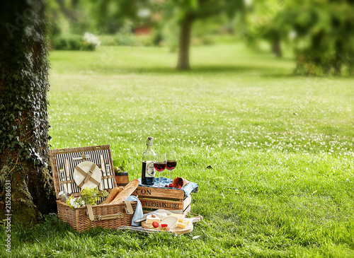 Picnic hamper under tree with glasses of wine photo