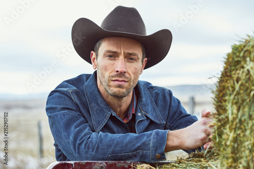 Cowboy leaning on his truck looking at camera seriously photo