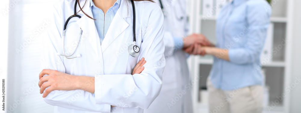 Female doctor standing straight in hospital. Closeup of stethoscope at practitioner breast. Medicine and health care concept Female doctor standing straight in hospital. Closeup of stethoscope at practitioner breast. Medicine and health care concept