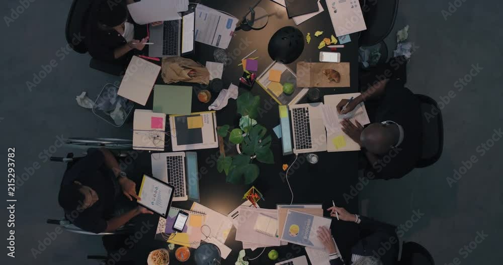 multi ethnic business people working late planning strategy for corporate project developing creative ideas in messy boardroom above view