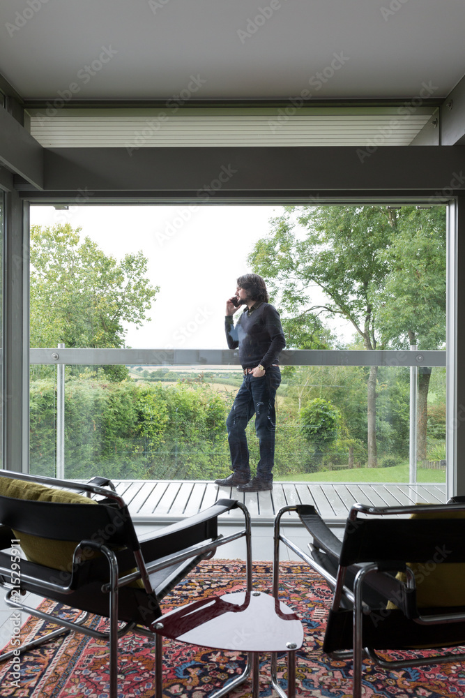 Man on the balcony of his modern home talking on the phone. Man on the balcony of his modern home talking on the phone.